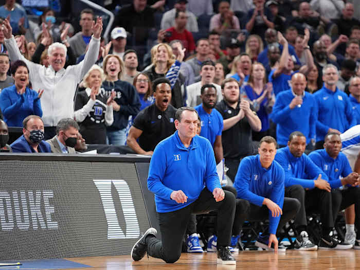 Coach K kneels while coaching